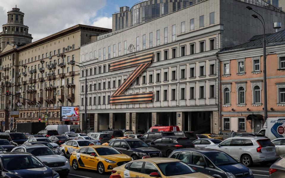 Cars stuck in traffic in front of a theatre building decorated with the letter Z in Moscow