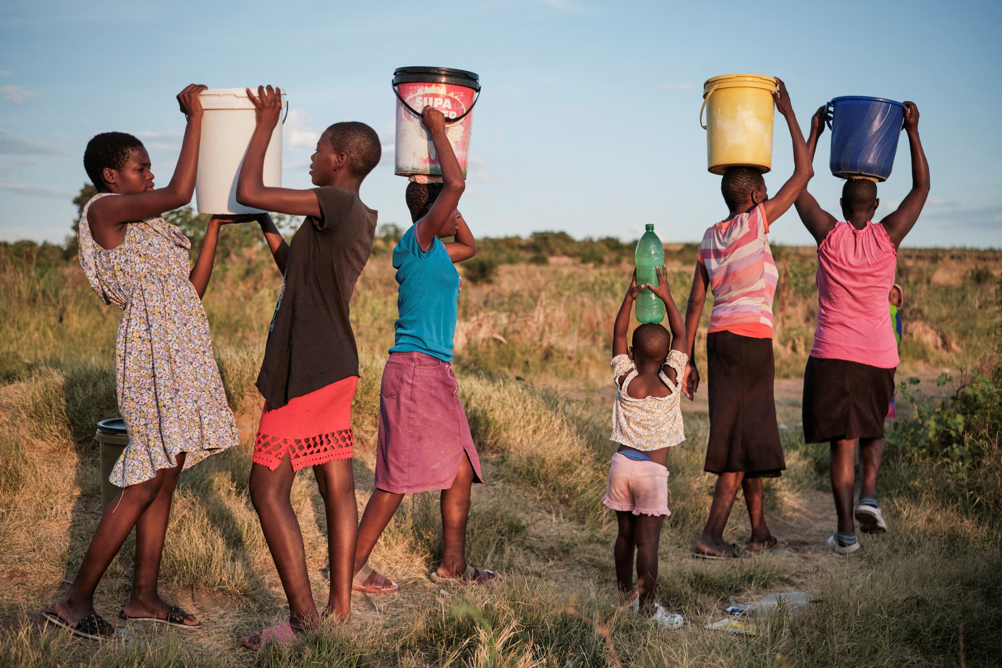 Cư dân thị trấn Pumula East ở Bulawayo - Zimbabwe trở về nhà sau khi lấy nước dùng từ giếng trong đợt nắng nóng và khô hạn đầu tháng 3-2024